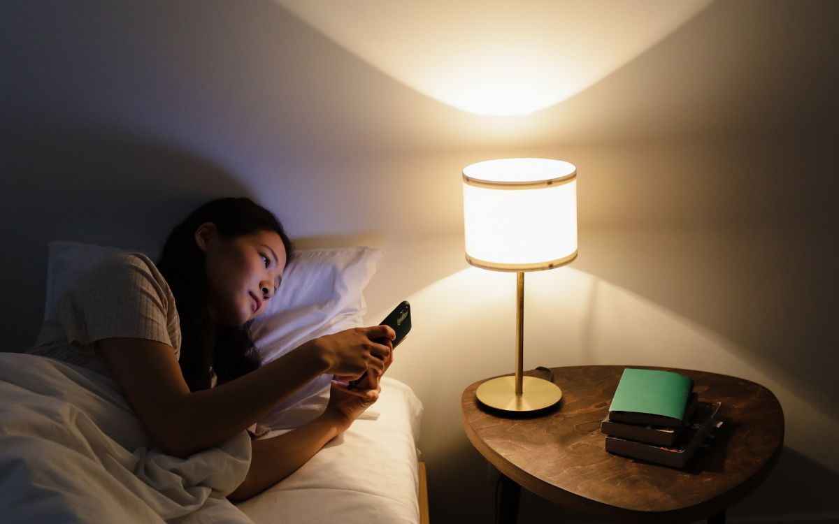 Woman in bed at night looking at smart phone.